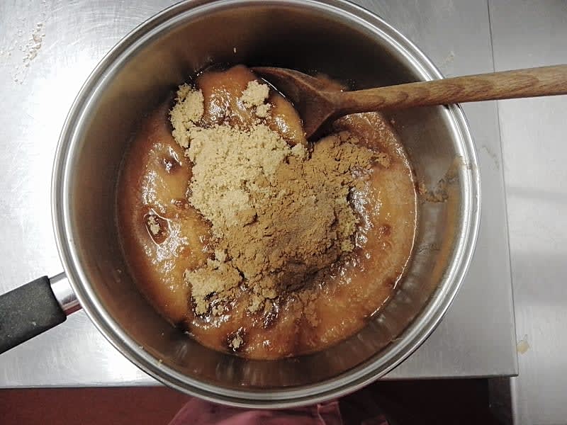 Brown sugar and spices in a saucepan stirred by wooden spoon